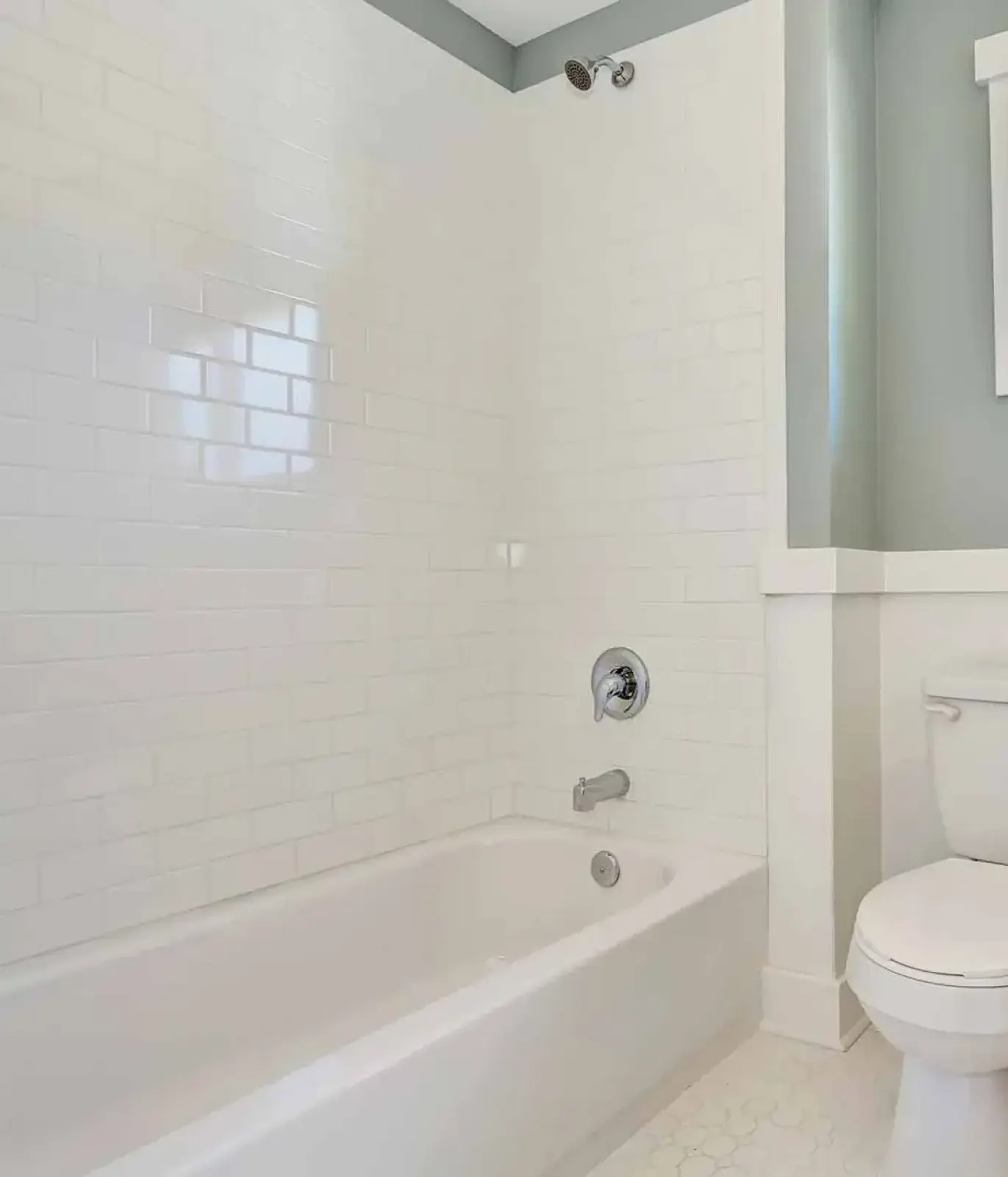 White subway tile bathroom with bathtub, chrome fixtures, and toilet